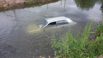 En marcha atrás, un automóvil terminó hundido en un canal de riego